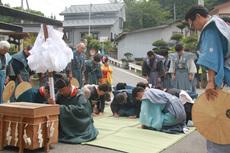神主さんがお祓い棒を持ちお祓いし、周りの方々はお辞儀をしている写真