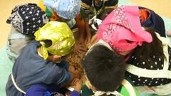 頭に三角巾を被った子供たちが味噌づくり体験をしている写真