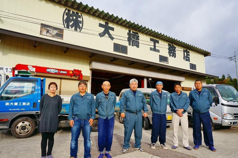 大橋工務店の建物の前に7名の従業員が並んで写っている写真