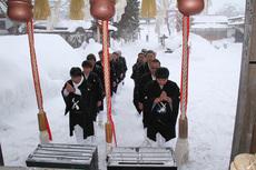 参道に雪が積もる中、わらじ履きのお党屋男衆がお千度参りをしている写真