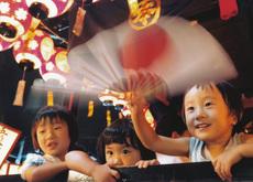3人の子供達のうちの1人が日本の国旗柄の扇子を持っている写真